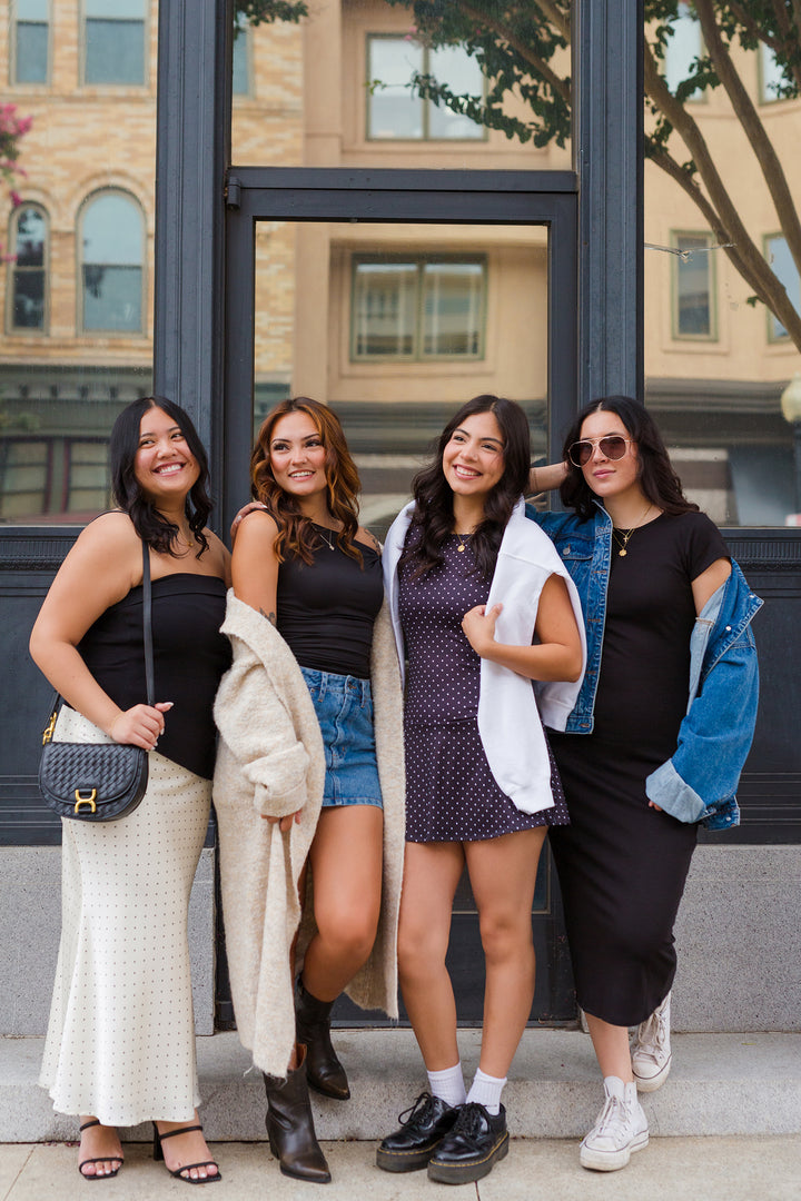 Four women posing together in front of a building