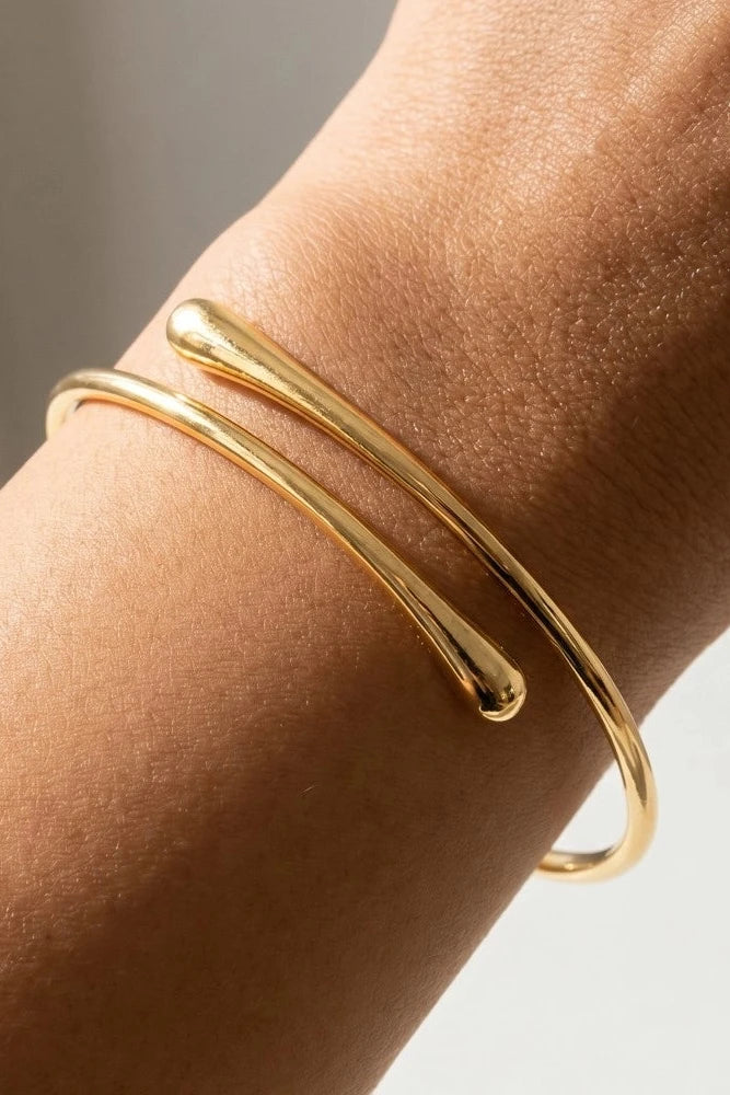 Gold bracelet on a wrist with a neutral background