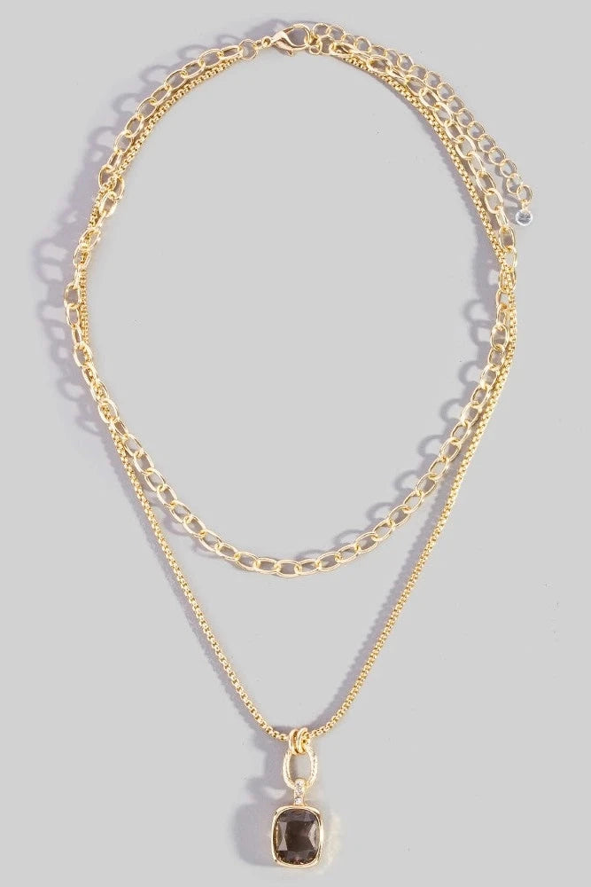 Gold chain necklace with a pendant on a gray background